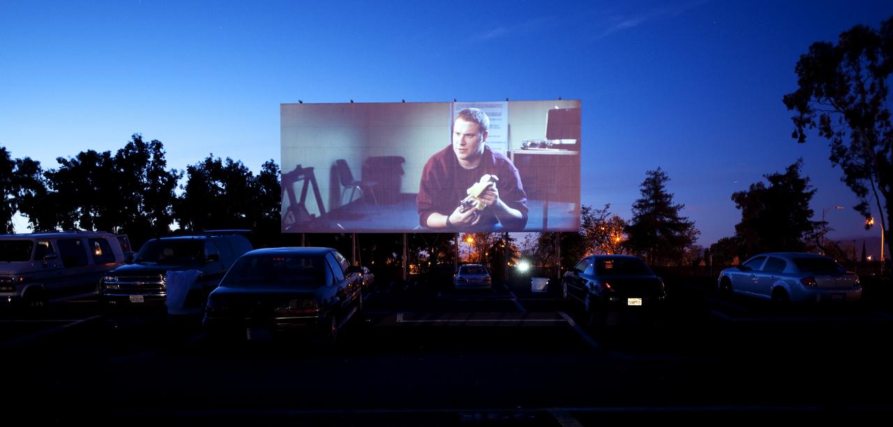 A drive-in movie theater screen glowing at dusk