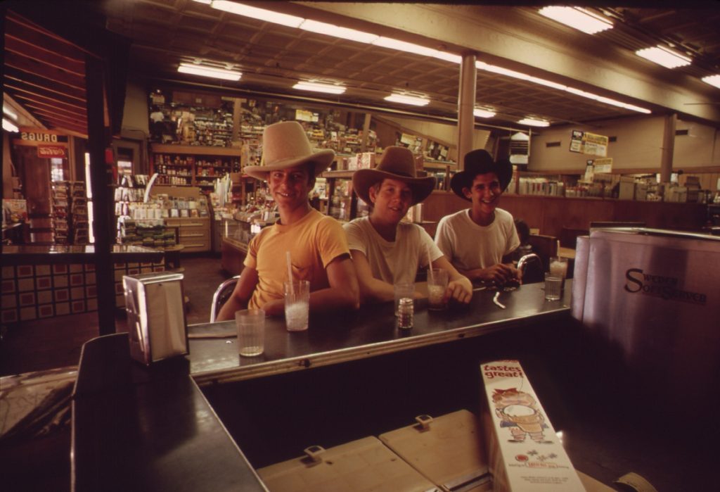 Three teenagers sitting with sodas at a drugstore lunch counter in Fort Worth, 1972