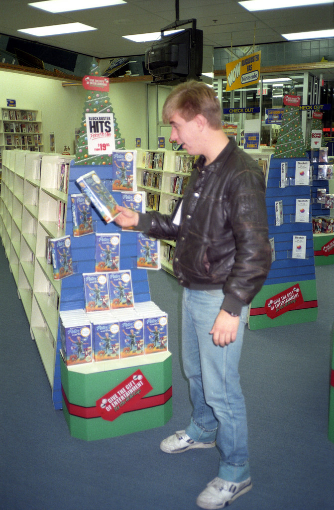 A customer choosing a VHS tape inside a Blockbuster Video store in 1990