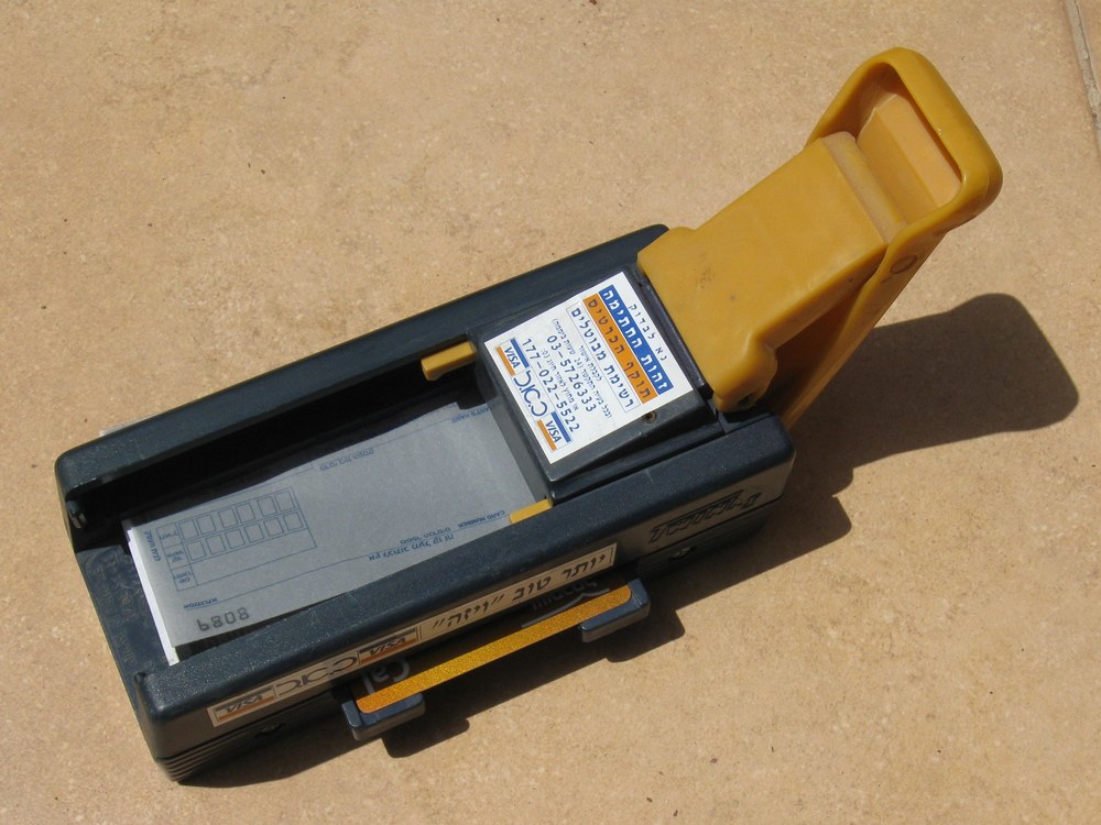 A manual credit-card imprinter holding an embossed card and multipart paper form
