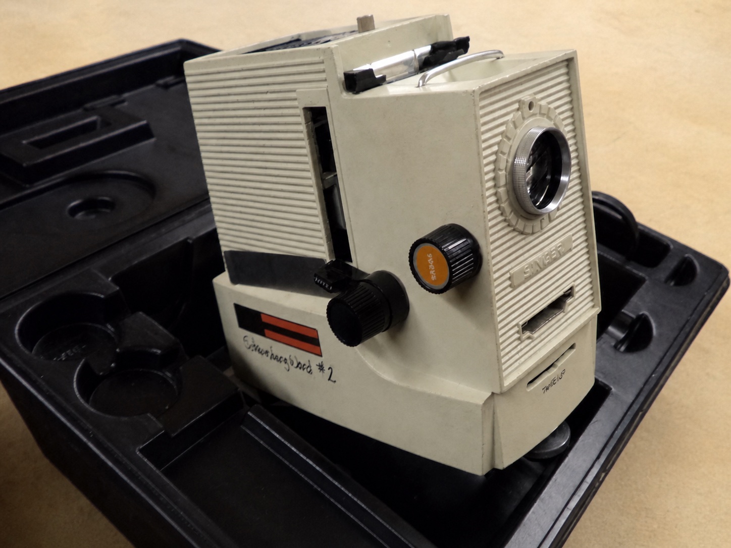 A beige Singer filmstrip projector with its lens, film gate, and controls visible