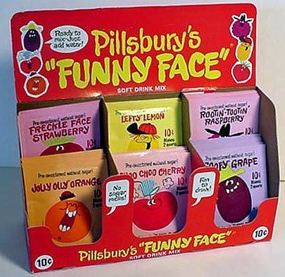 A Pillsbury Funny Face counter display holding packets of Freckle Face Strawberry, Lefty Lemon, Rootin'-Tootin' Raspberry, Jolly Olly Orange, Choo Choo Cherry and Goofy Grape