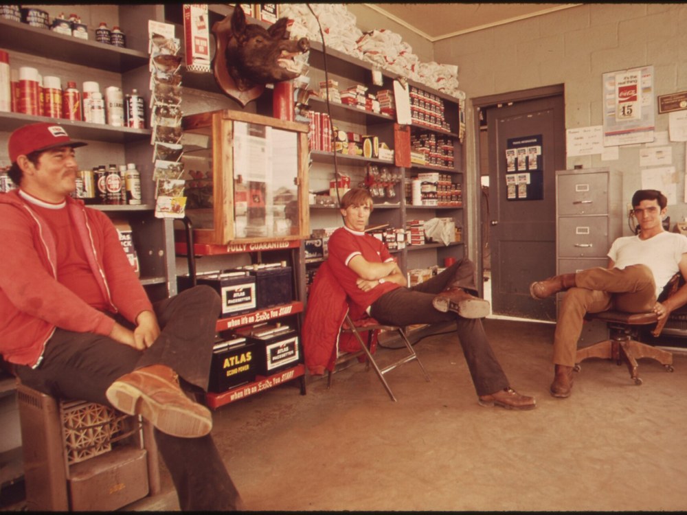 Three attendants seated inside a small gas station in Leakey, Texas, in the 1970s