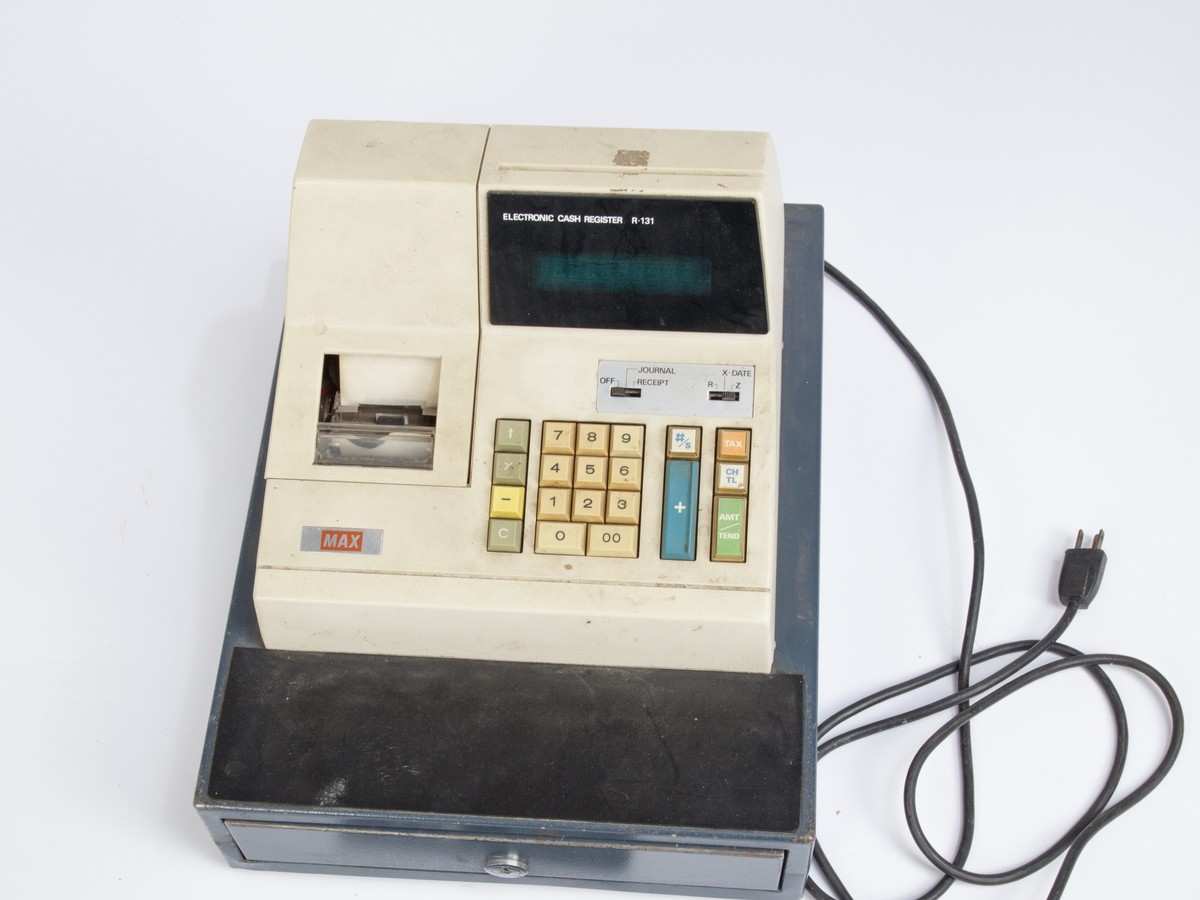 A cream-and-blue electronic cash register with numeric keys, receipt printer, and cash drawer