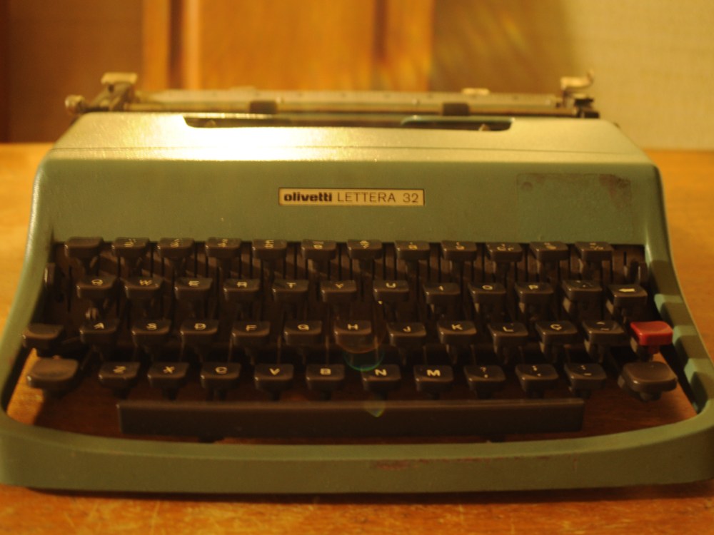 A green Olivetti Lettera 32 manual typewriter with black keys and a metal carriage