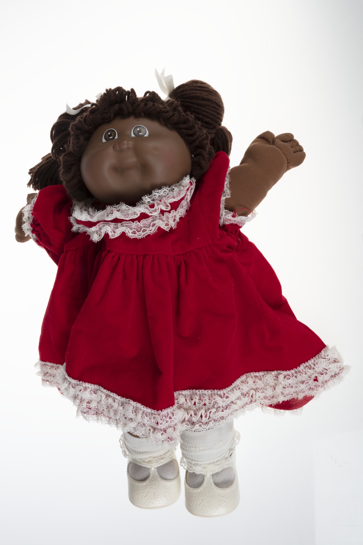 A 1984 Black Cabbage Patch Kid doll wearing a red velvet dress with white lace trim