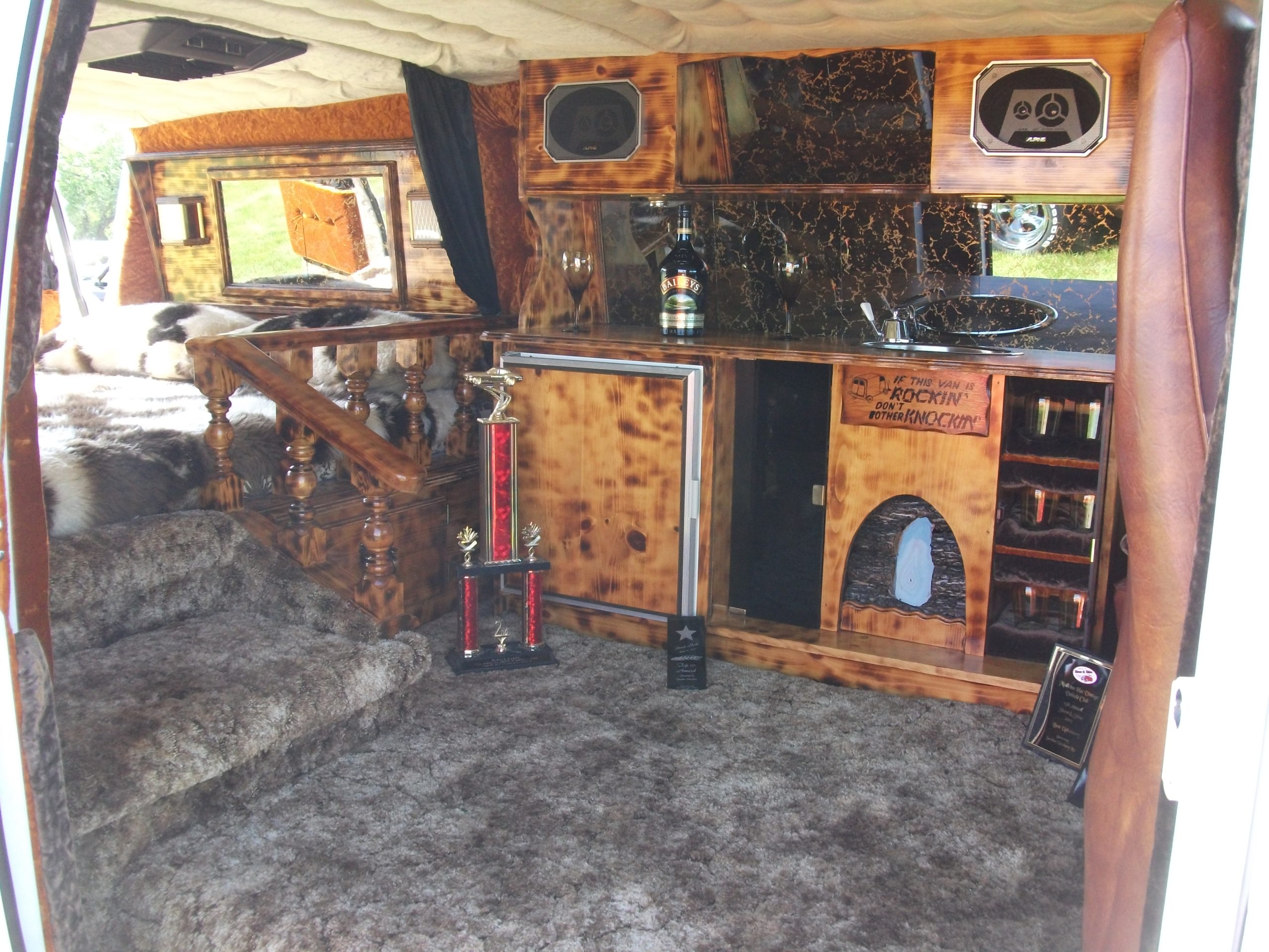 Shag carpet, wood cabinetry, speakers, and a sink inside a customized Chevrolet van.