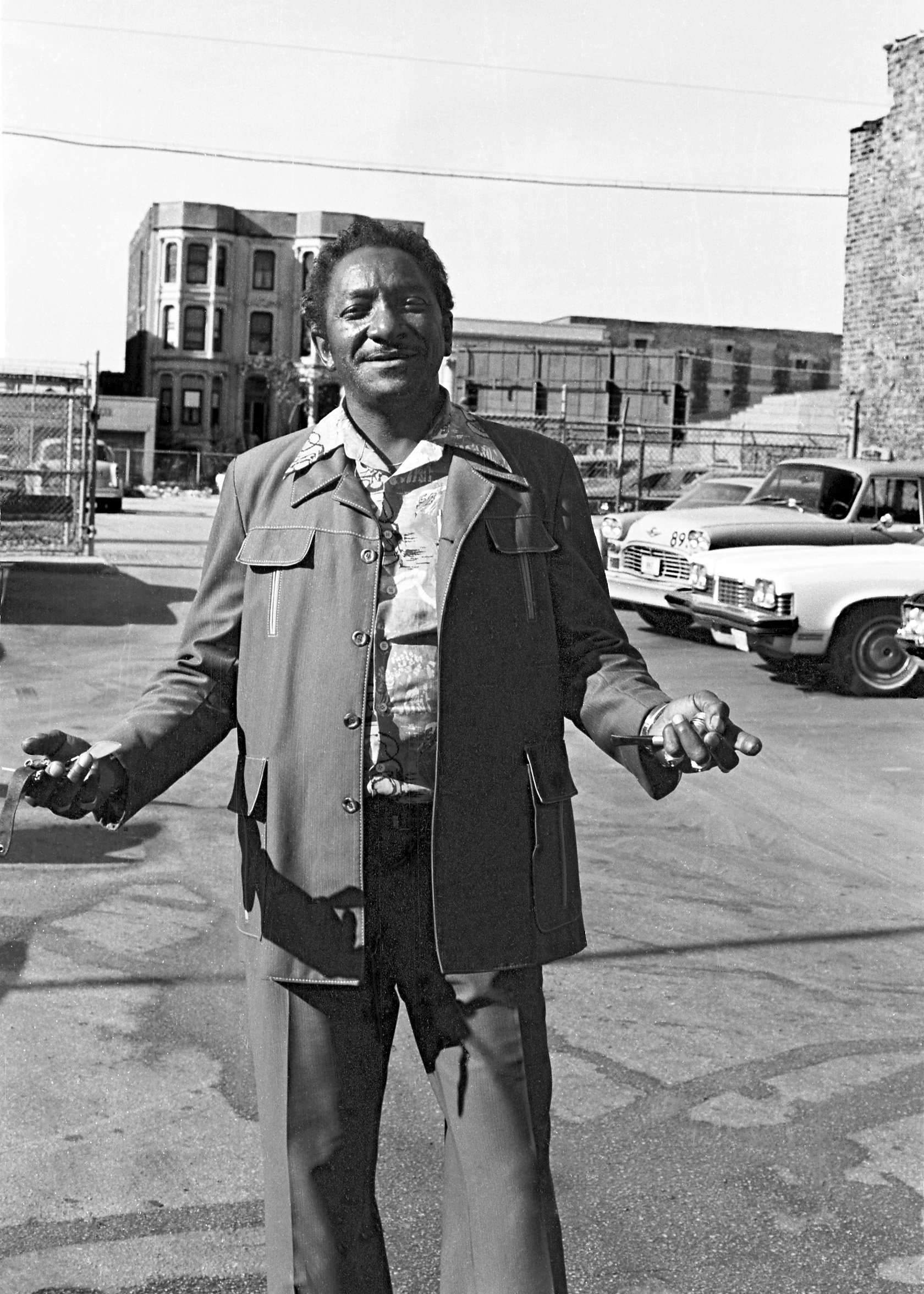 A man wearing a leisure suit with wide lapels stands in a Chicago parking lot.