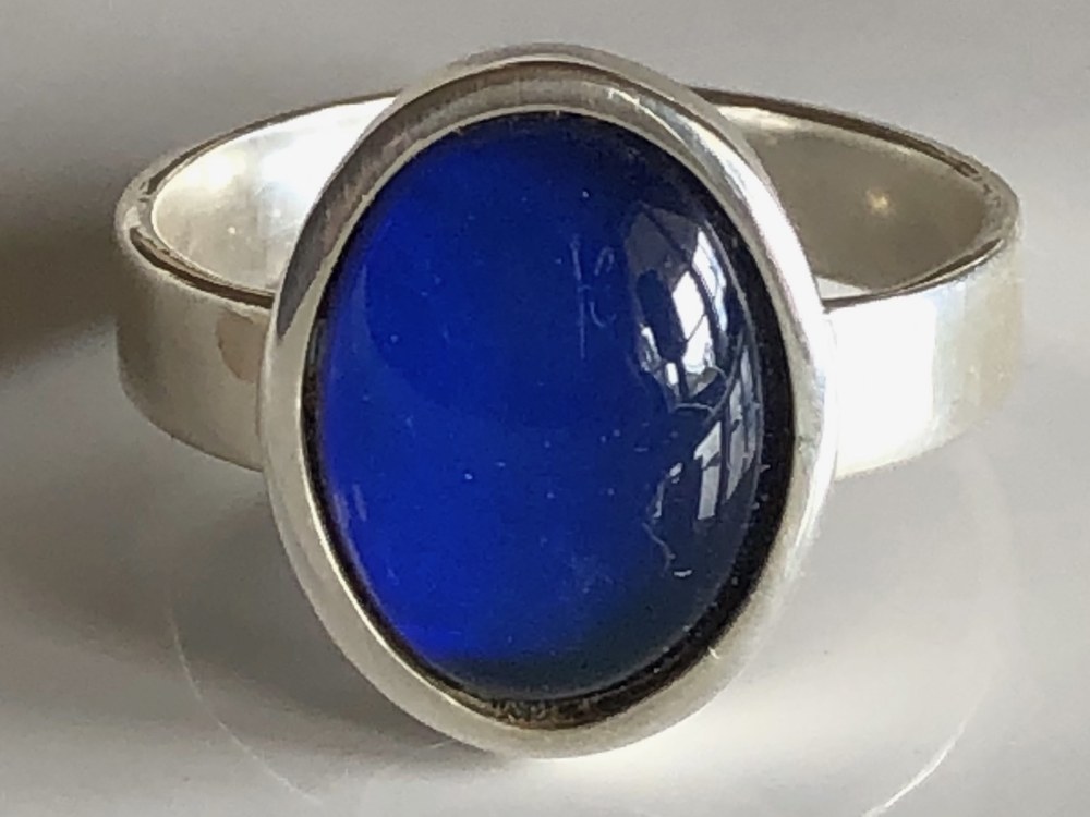 A sterling silver mood ring with an oval stone showing deep blue