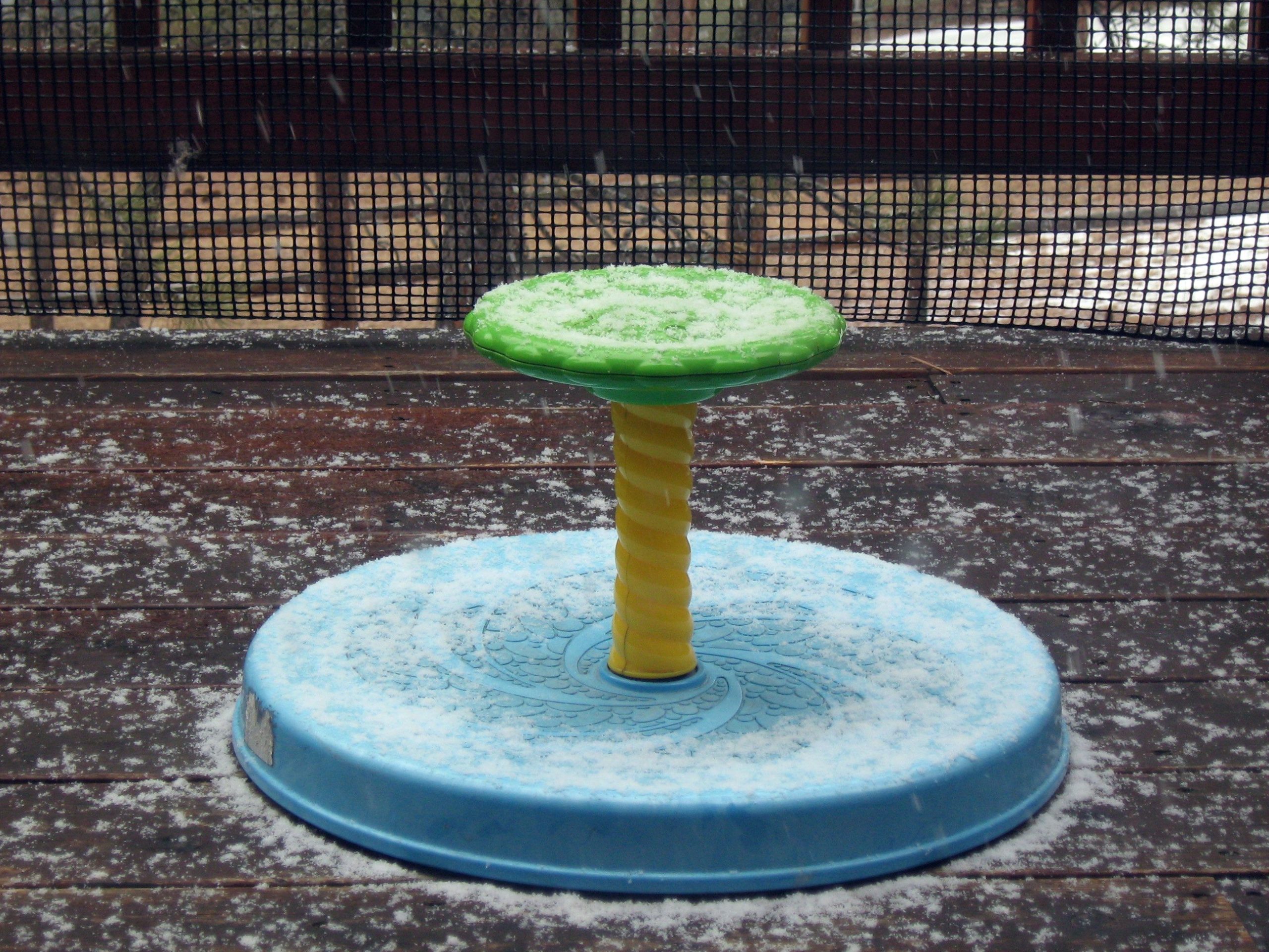 A Playskool Sit ’n Spin with snow resting on its round base and center wheel