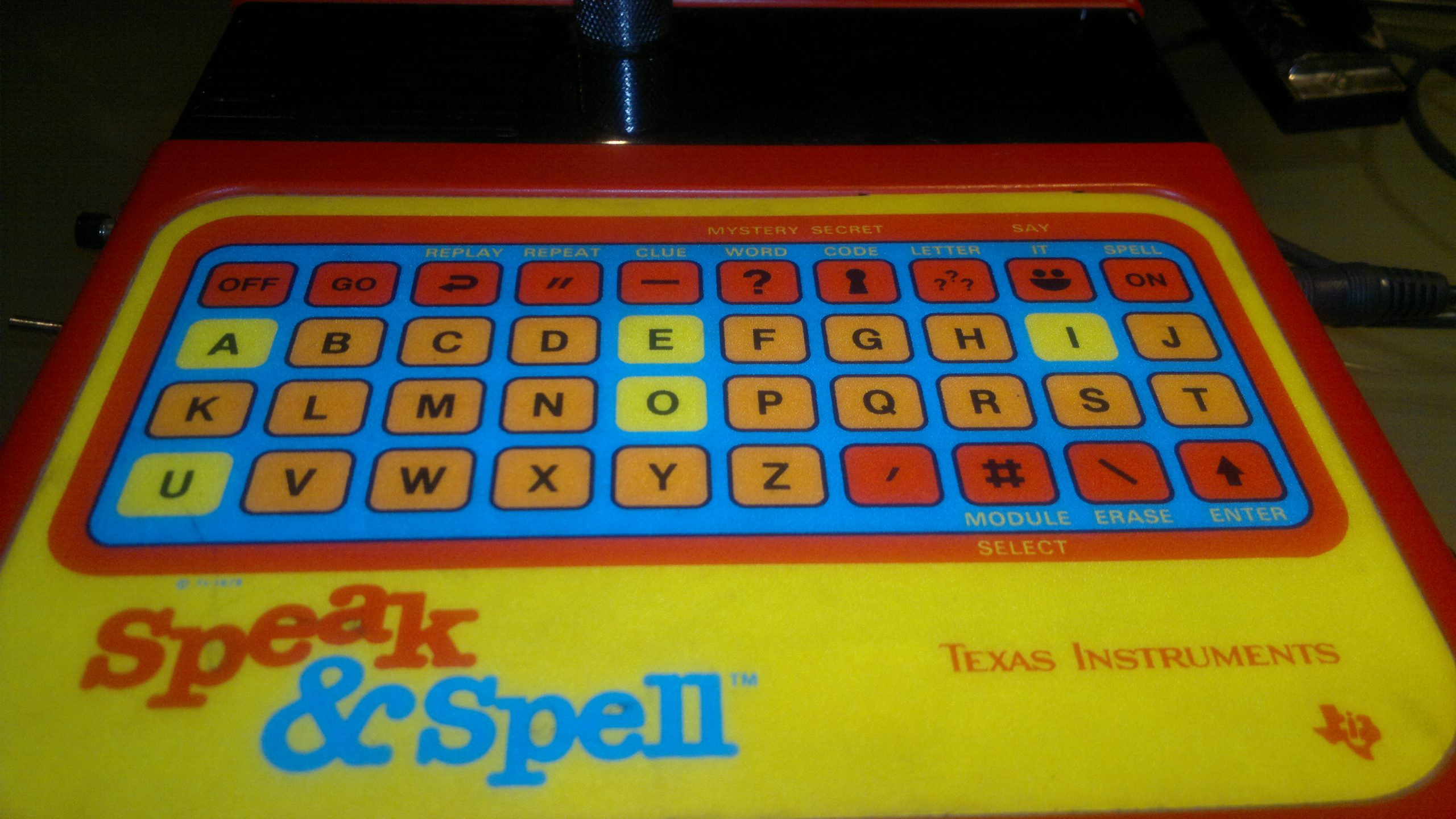 An orange Texas Instruments Speak & Spell with its keyboard, display, and carrying handle