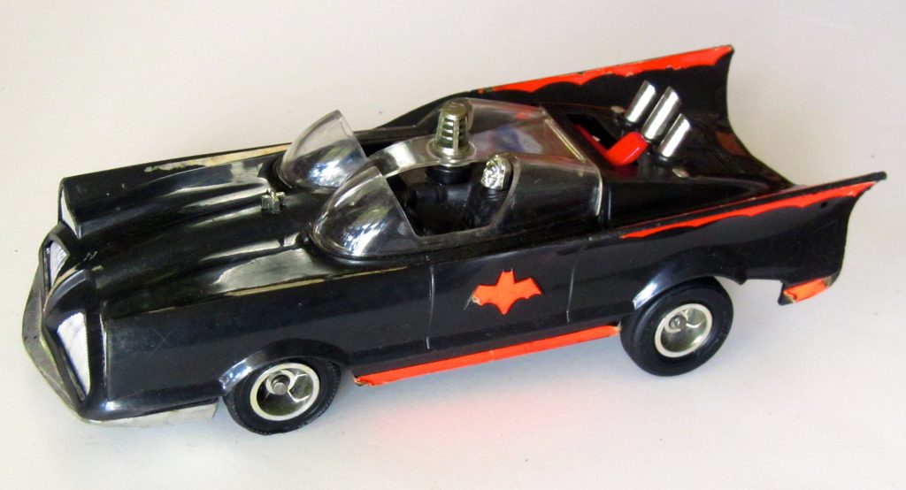 A black plastic Mattel Switch ’n Go Batmobile toy with red bat emblems, twin clear bubble canopies and chrome exhaust pipes