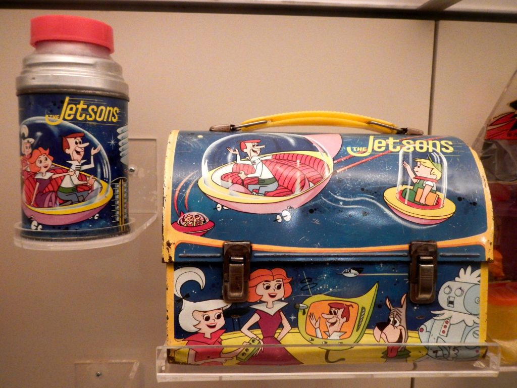 A metal dome-top Jetsons lunch box showing George, Judy, Jane, Elroy, Astro and Rosie, beside a matching Jetsons thermos with a red cap