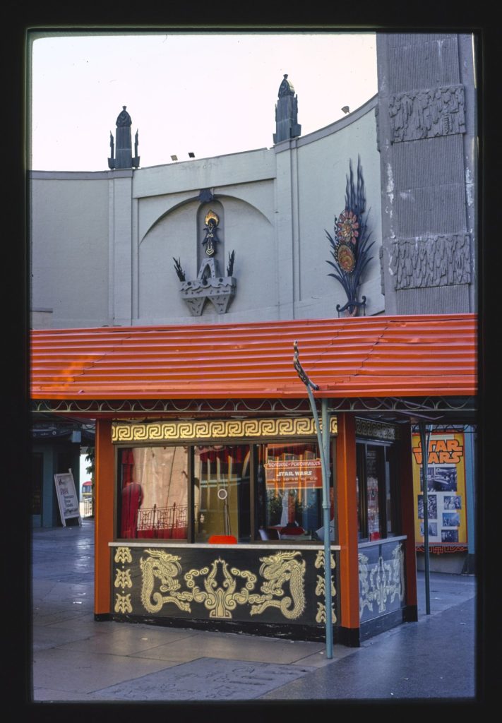 The red-roofed ticket booth of the Chinese Theater in Hollywood, with a Star Wars sign in its window and a Star Wars poster case beside it.