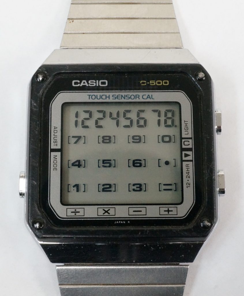 A silver Casio TC-500 calculator watch reading Touch Sensor Cal, with number keys 0 to 9 and math symbols printed on its square face