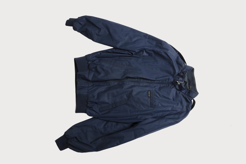 A navy blue Members Only racer jacket laid flat with knit cuffs and waistband, a snap collar and a small Members Only label on the chest pocket