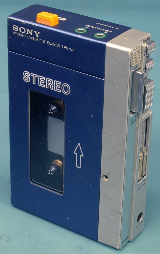 A blue and silver Sony TPS-L2 stereo cassette player with a window showing the tape reels, an orange button and two headphone jacks labeled A and B
