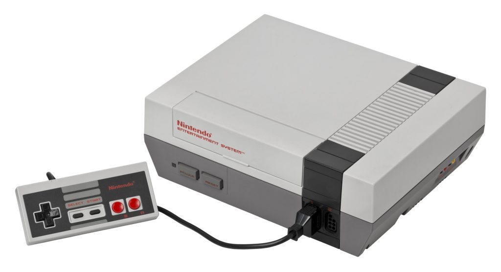 A gray Nintendo Entertainment System console with a rectangular controller plugged into its front port.